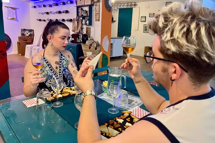 Two people enjoy a sunset wine and cheese tasting in Cordoba, examining glasses of local wine with cheese platters.