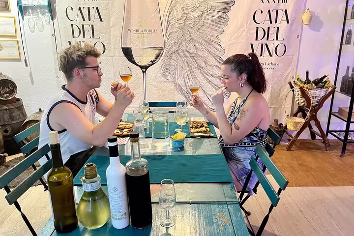 Couple enjoying Cordoba sunset experience with local wine and cheese tasting at a cozy wine cellar.