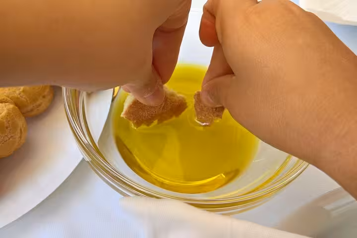 Hands dipping fresh bread in local olive oil during a Corfu private tour, tasting authentic Greek flavors