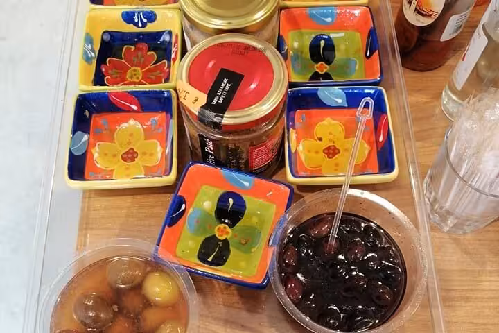 Corfu private tour food tasting with Greek olives, jam jars and colorful dishes at a local Corfu shop