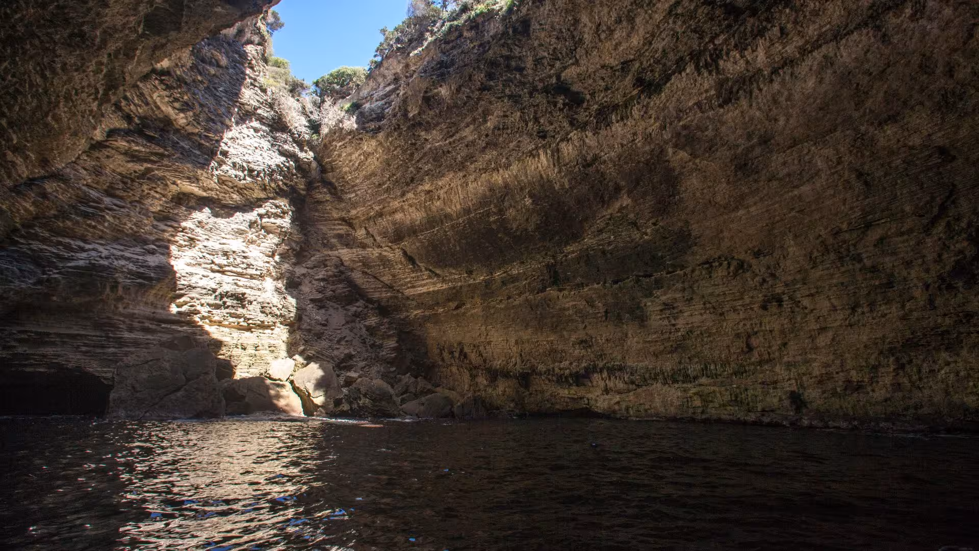 Majestic rock formations inside a coastal cave in southern Corsica, illuminated by sunlight filtering through the entrance.