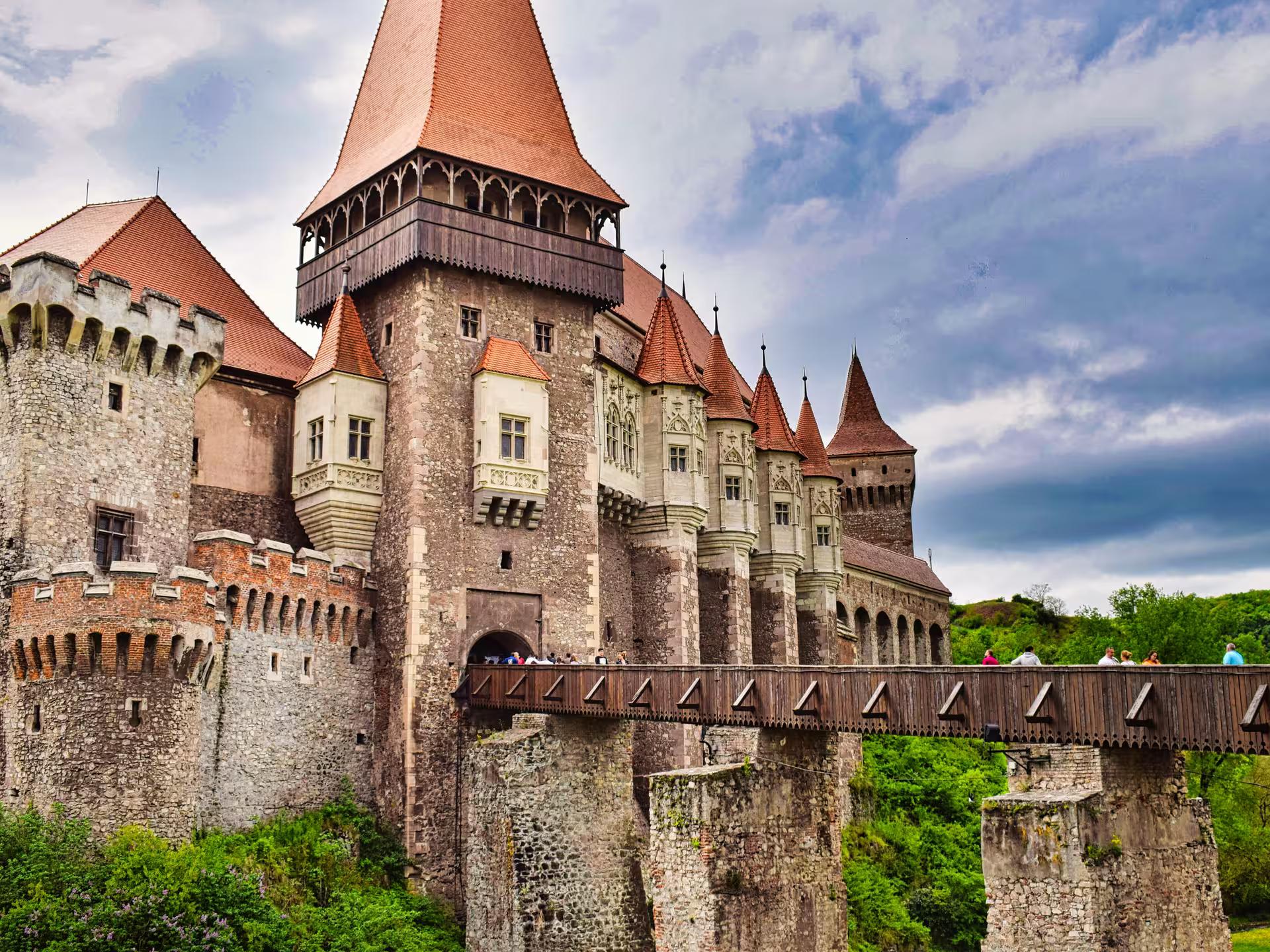 Majestic Corvin Castle with red-roofed towers and wooden bridge on Best of Transylvania guided tour