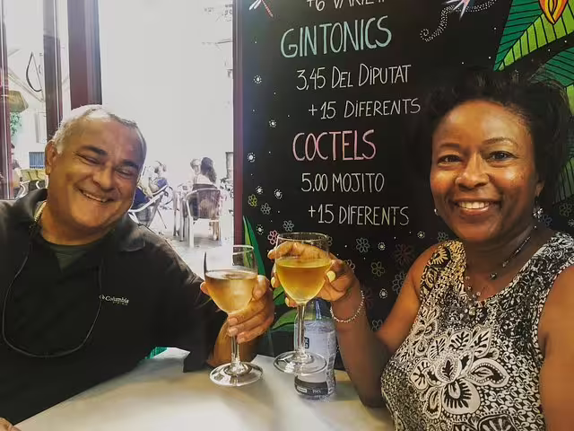 Couple enjoying drinks at a traditional Barcelona tavern during a food and drink private tour, with cocktail menu in background.