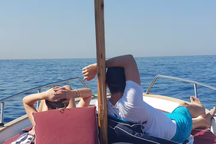 Couple relaxing on a classic boat sun deck on a private 4-hour Capri tour, cruising the Tyrrhenian Sea