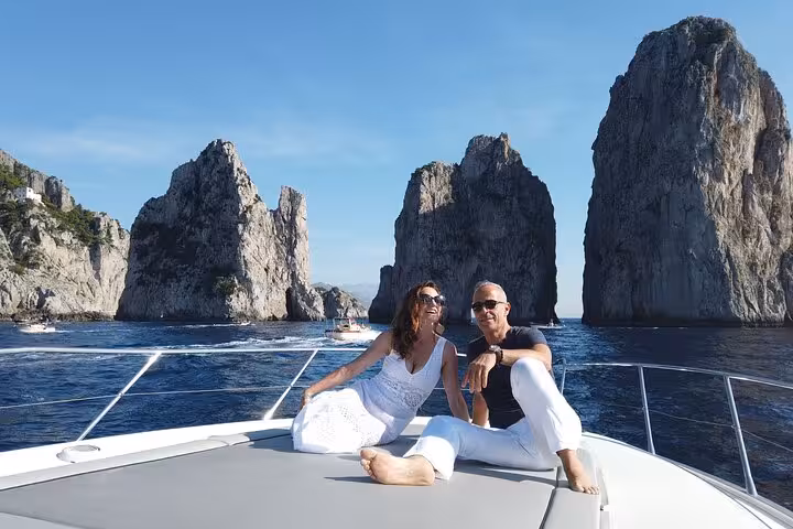 Couple enjoying a luxurious boat tour near the iconic Faraglioni rocks on the Sorrento Coast.