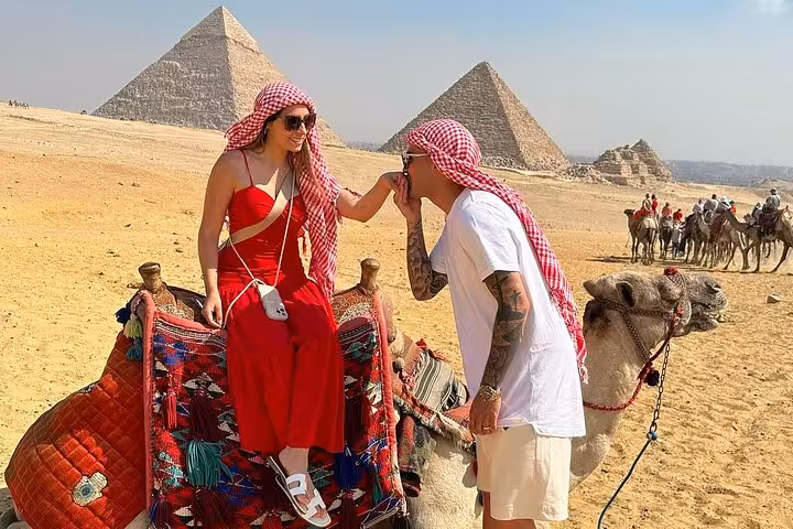 Couple on camel ride at Giza Pyramids in Cairo, Egypt, classic desert photo on guided tour experience