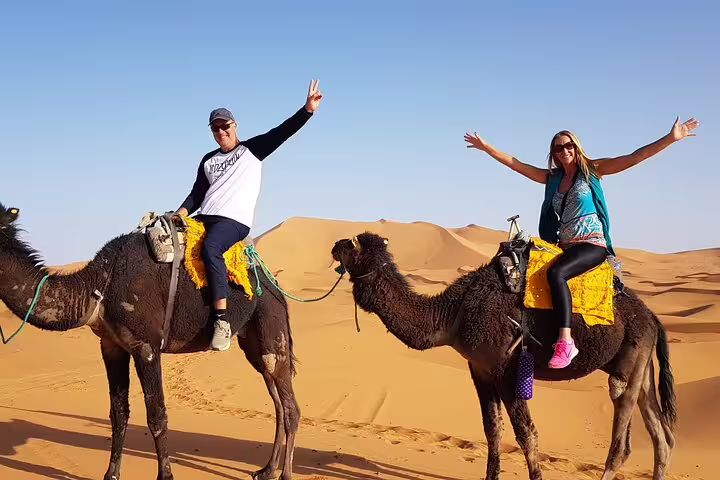 Couple riding camels on Merzouga Erg Chebbi dunes, 3-day private desert tour from Marrakech