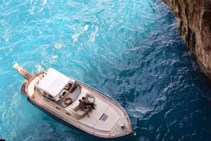 Couple relaxing on a boat under stunning cliffs during a Capri small group tour from Positano.