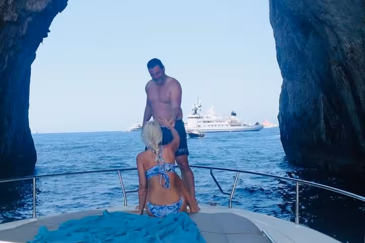Couple on a boat tour between Capri's dramatic sea cliffs, offering breathtaking views and a unique maritime experience.