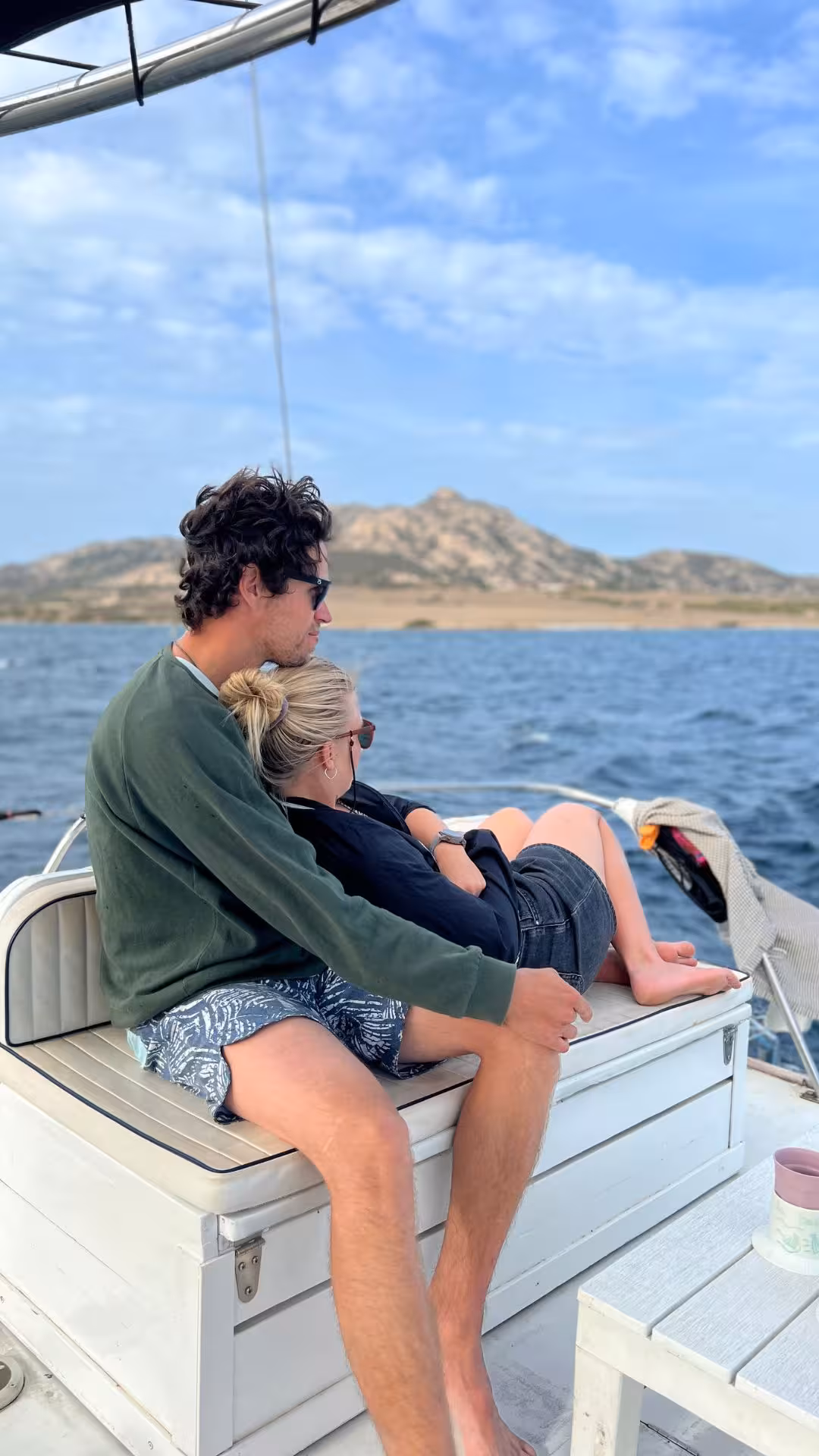 Couple enjoying a scenic catamaran trip in the Gulf of Asinara, with stunning coastal views and clear blue skies.