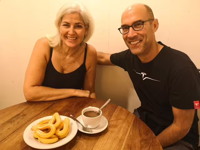 Smiling couple enjoying churros and hot chocolate in a cozy Barcelona tavern during a food and drink private tour.