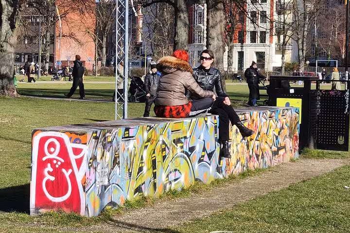 Couple sitting on colorful graffiti-covered bench in a vibrant Copenhagen park during a walking tour.
