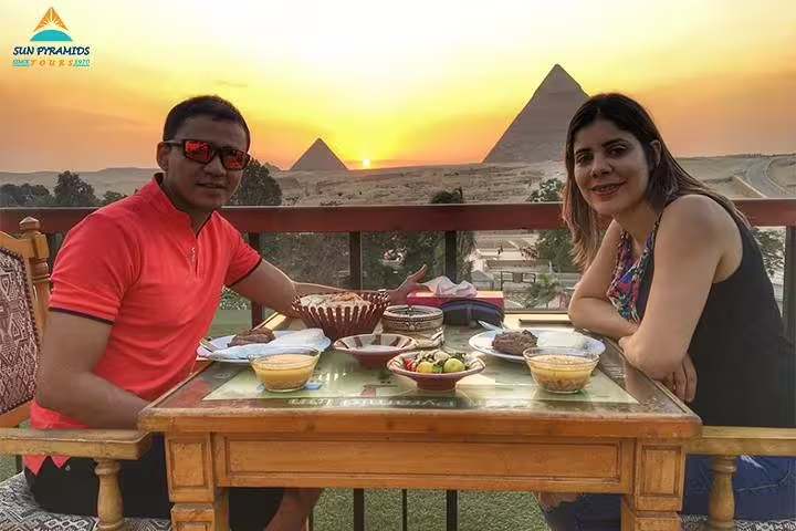 Couple dining at sunset with Giza Pyramids view, part of Cairo tour covering Sphinx, Memphis, Saqqara and Dahshur
