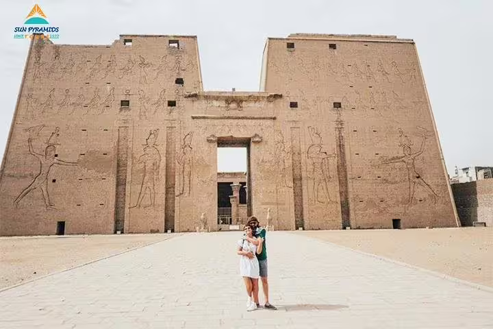 Couple at Edfu Temple entrance in Aswan region, part of 15-day 14-night Egypt tour with Pyramids and oasis