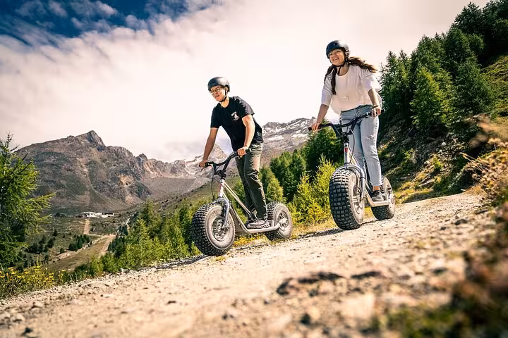 Couple riding off-road e-scooters in the Swiss Alps valley, adventure add-on for 4 day trekking tour