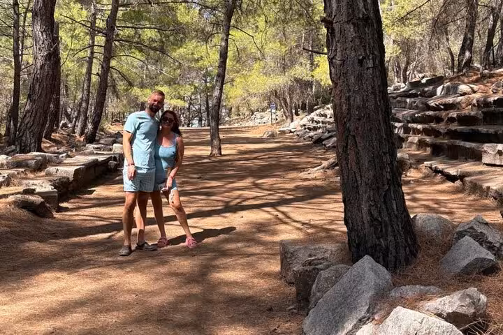 Couple exploring a serene forest path in Turkey's hidden villages, surrounded by ancient stone ruins and tall trees.
