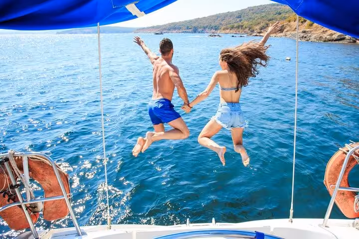 Couple holding hands and jumping into the clear blue waters from a boat on a Positano and Amalfi Coast tour.