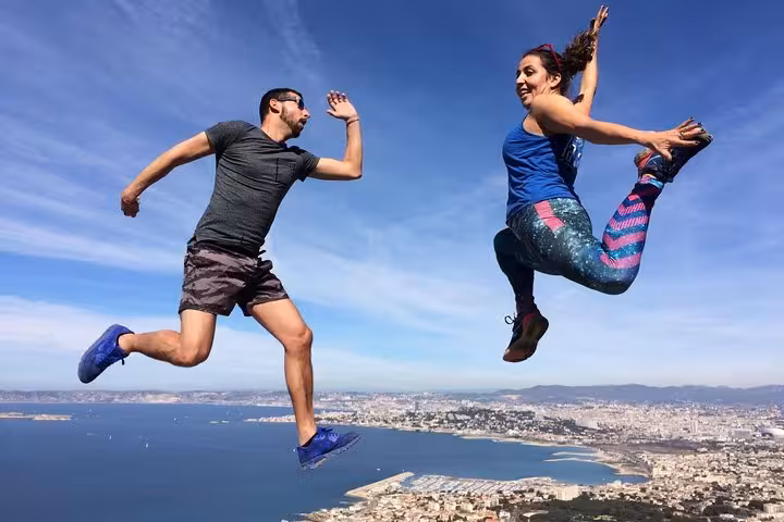 Couple jumping on a Calanques summit above Marseille coastline, fun moment on a 3-day Calanques adventure tour