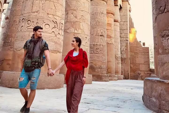 Couple walking among Karnak Temple pillars, Luxor sightseeing on Cairo to Luxor sleeper train tour package