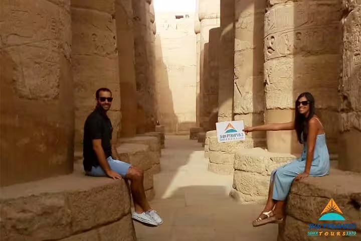 Couple relaxing between ancient Luxor temple columns, part of the 8-day Luxor Nile cruise and Cairo itinerary