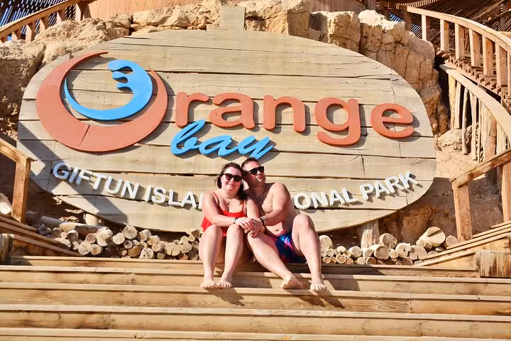 Couple at Orange Bay Giftun Island sign, Hurghada boat trip stop for snorkeling and lunch in Red Sea