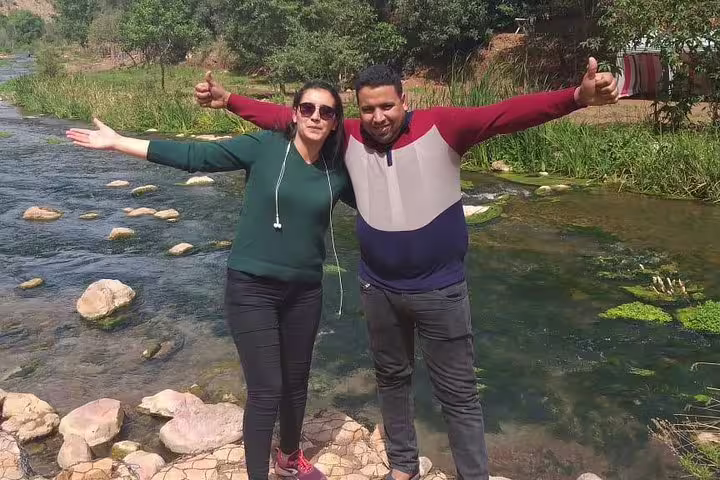 Couple posing by a clear river near Ouzoud Falls on a private Marrakech day trip with local guide
