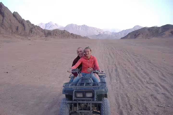 Couple riding a quad bike in Sinai Desert on a private Sharm El Sheikh ATV safari with mountain views