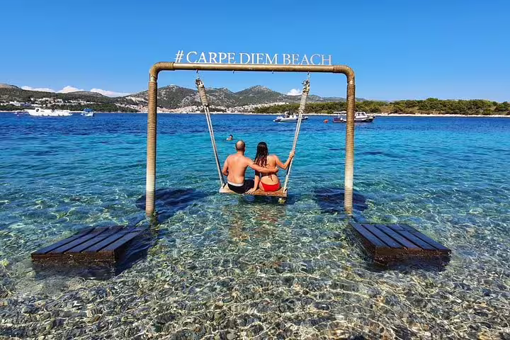 Couple on sea swing at Carpe Diem Beach, Hvar stop on Scheduled Blue Cave & 5 Islands tour Croatia