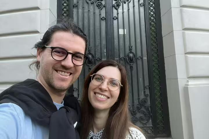 Couple smiling in selfie in front of ornate iron gate in Bucharest Old Town
