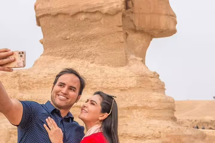 Couple taking a selfie by the Great Sphinx of Giza on a private guided tour with hotel transfers and entry tickets