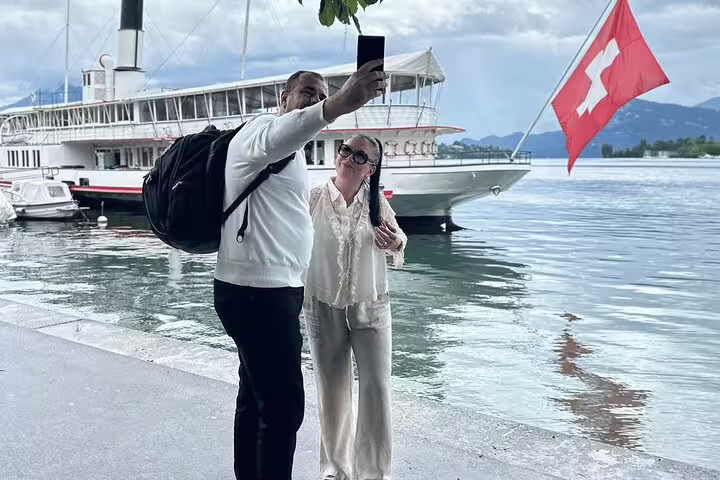 Couple taking a selfie by a Swiss flag-adorned boat on Lake Lucerne during a private day trip.