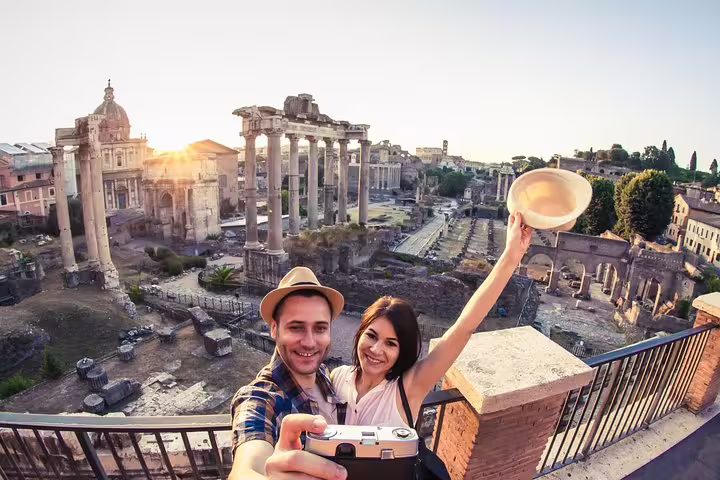 Happy couple taking a selfie above the Roman Forum ruins at sunset during a private Colosseum and Forum guided tour in Rome