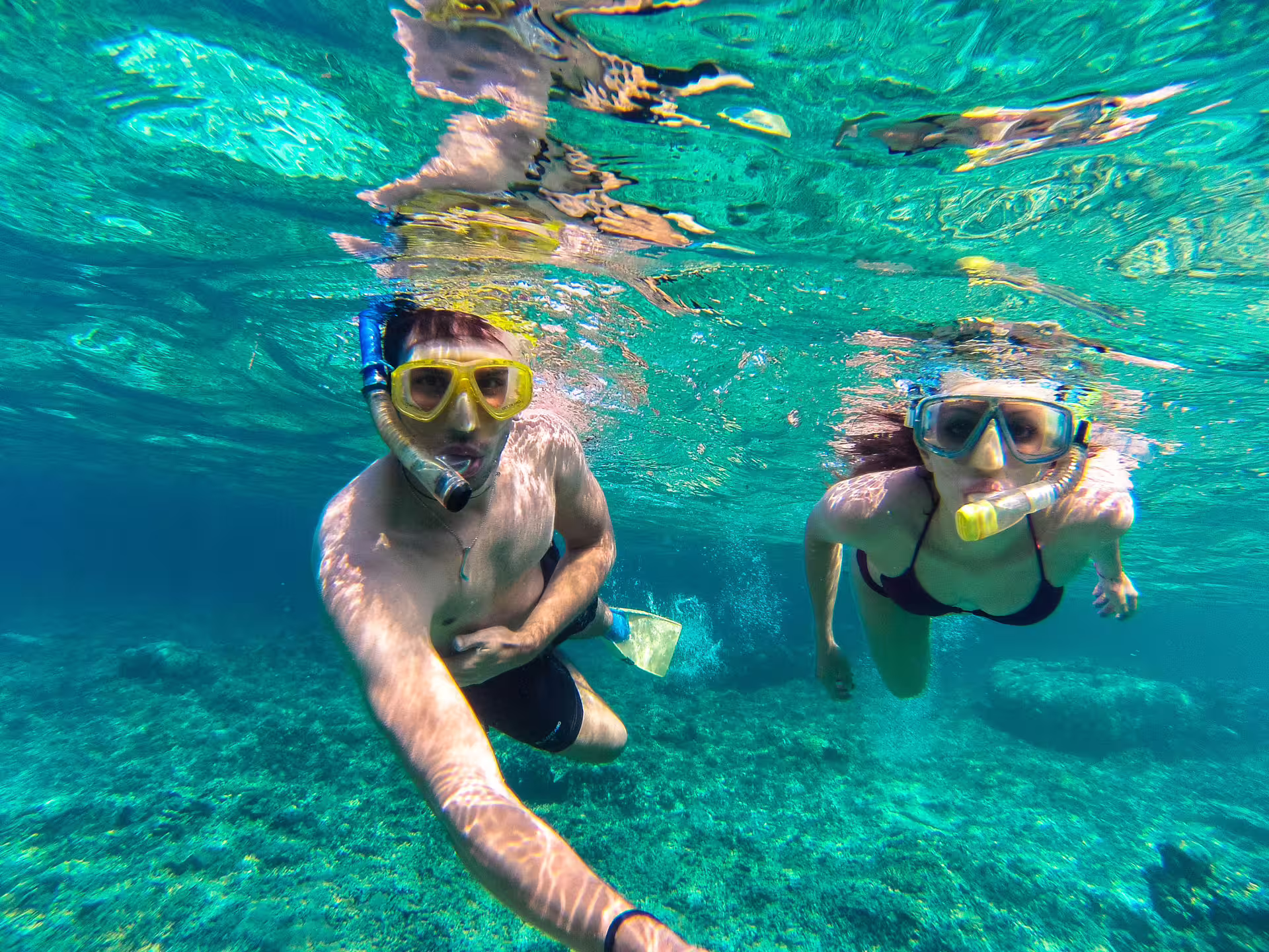 Couple snorkeling in crystal-clear Capri waters, enjoying a guided boat excursion with vibrant underwater views