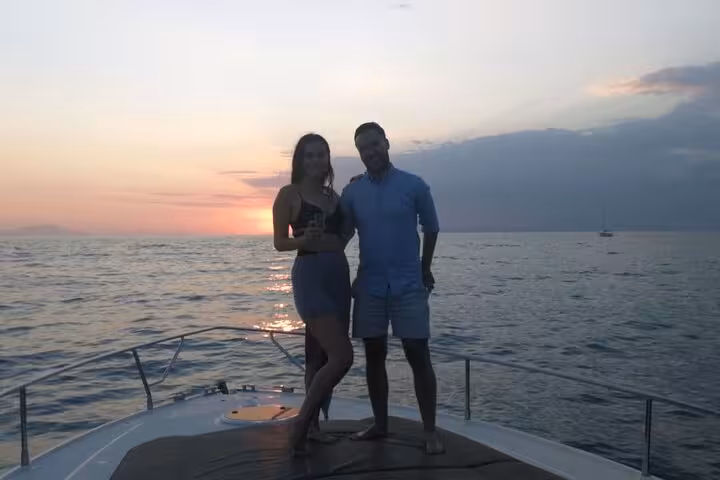 Couple standing on a boat deck at sunset during a private ocean cruise.