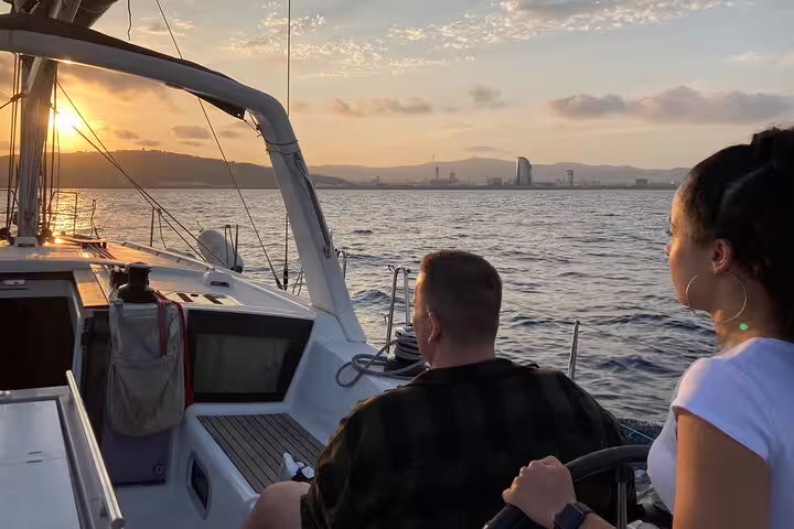 Couple enjoying a scenic sunset sailing experience with open bar and tapas, capturing stunning coastal views.