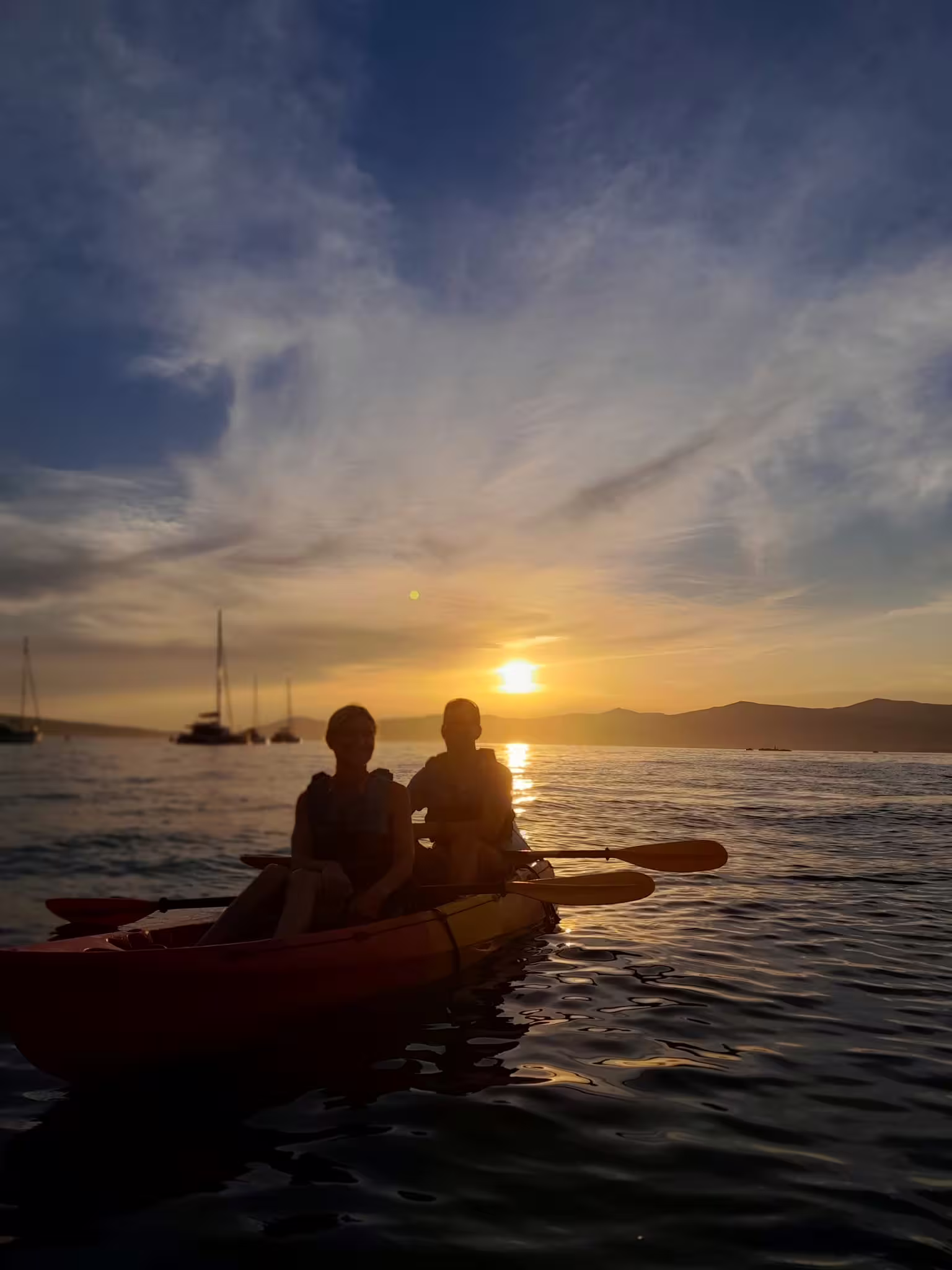 Couple paddling tandem sea kayak at golden sunset in Split, Croatia, on guided wine sea kayaking tour