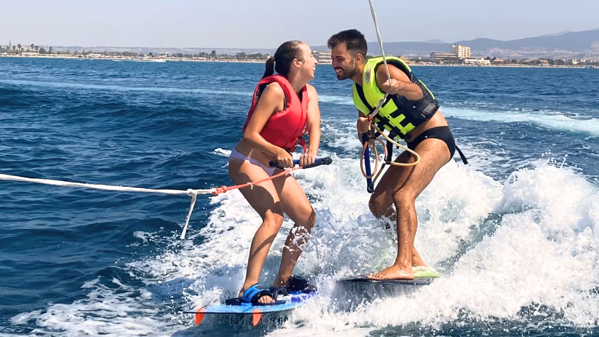 Couple enjoying tandem wakeboarding in Golfo degli Angeli, Cagliari with scenic views.
