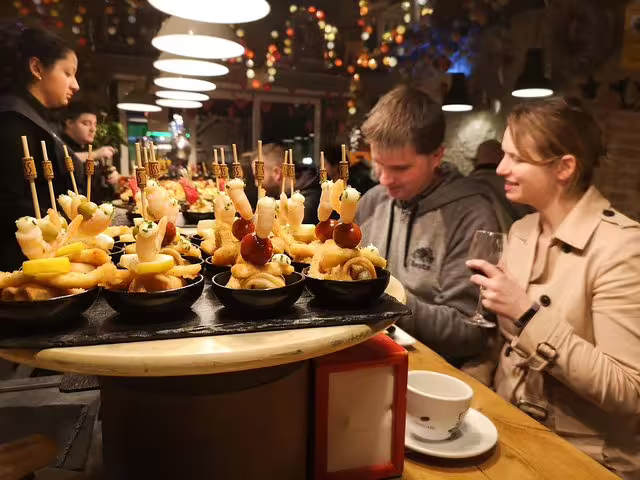 Couple enjoying tapas in a cozy Barcelona tavern during a private food and drink tour, surrounded by vibrant decor and atmosphere.