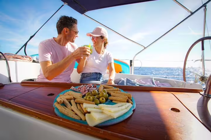 Couple toasting drinks beside tapas on a yacht table during a gourmet sailing experience in Barcelona, Spain
