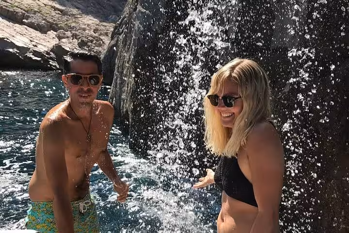 Happy couple enjoying a refreshing waterfall on a private boat tour to Capri from Sorrento.