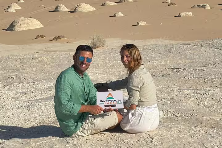 Couple seated in Egypt’s White Desert with chalk rock formations on Bahariya Oasis overnight camping tour