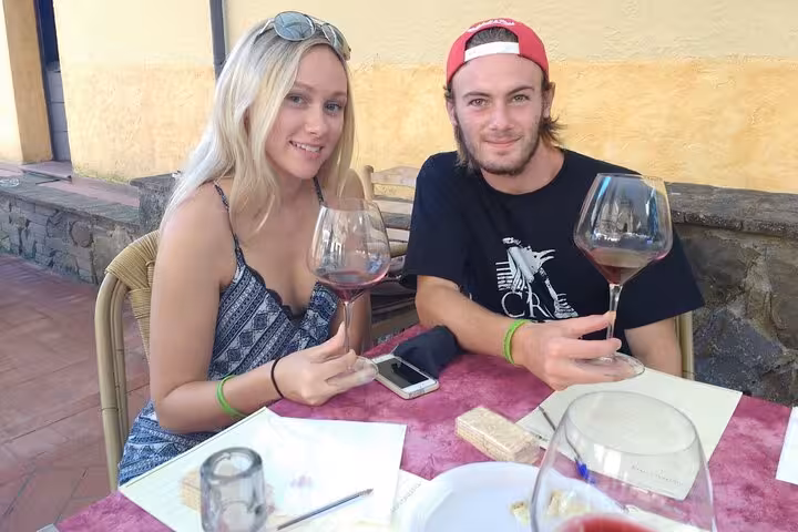 Couple savoring wine at an outdoor tasting in Tuscany, part of a day trip from Rome with lunch included.