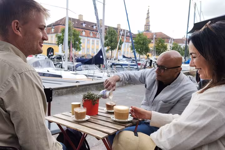 Tourists enjoying coffee and conversation at a waterfront cafe during a cultural walking tour.