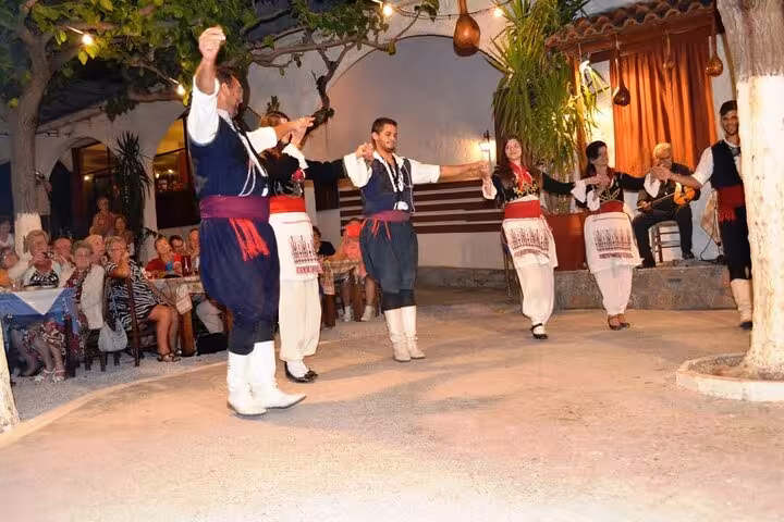 Cretan folk dance show in traditional costumes at a taverna, part of Cretan Night music, food and dancing tour