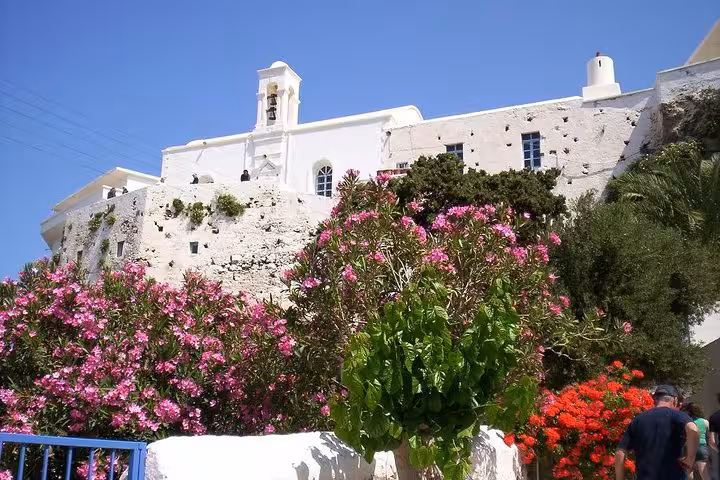 Whitewashed Cretan monastery with blooming flowers, scenic stop on private day trip to Elafonissi Beach from Chania