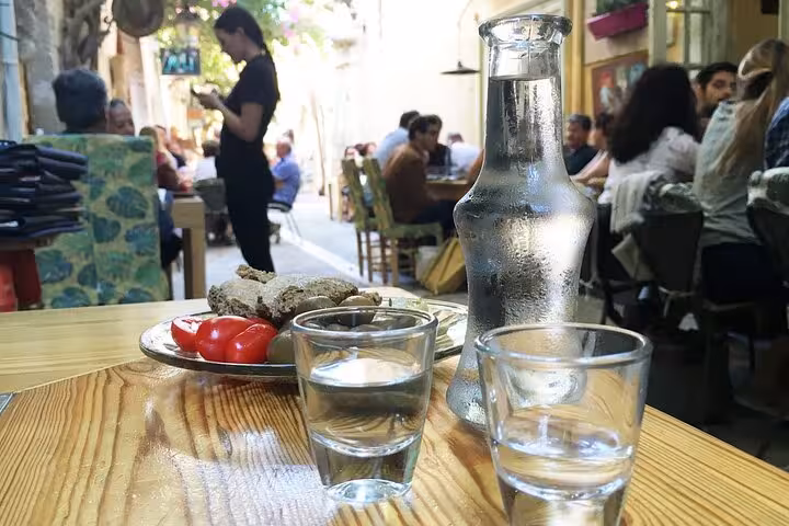 Cretan night dinner table with raki, water carafe and meze at a local taverna, authentic Crete food tour