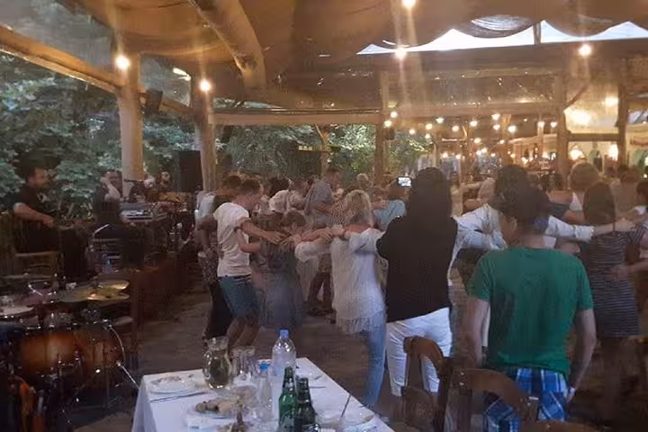 Guests join a Cretan night tour with live music, taverna dinner and Greek folk dancing under string lights