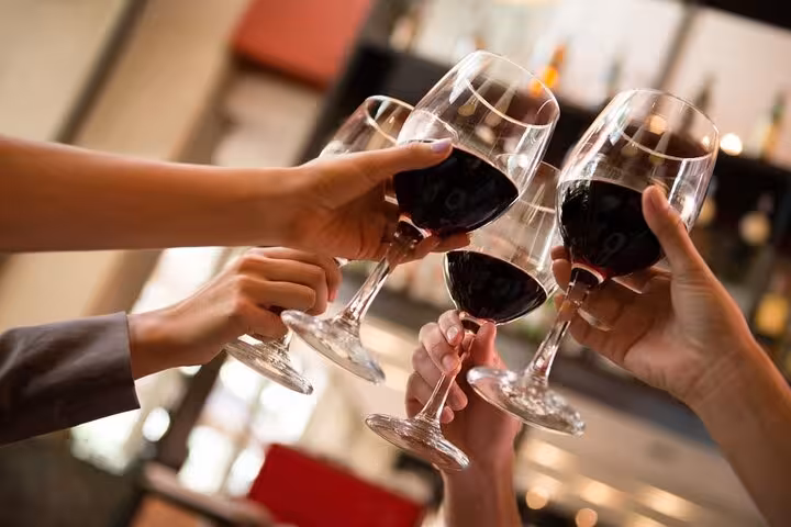 Guests clinking glasses of Cretan red wine at a traditional Cretan Night with dinner, music and dancing