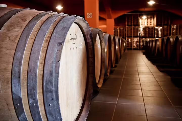 Rows of wooden wine barrels aging in a dimly lit cellar, capturing the essence of Heraklion's village wine culture.