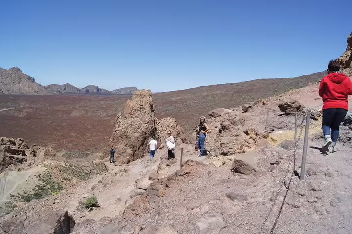 Visitors explore the rocky landscape of Teide National Park under clear skies, a must-see for cruise ship excursions.